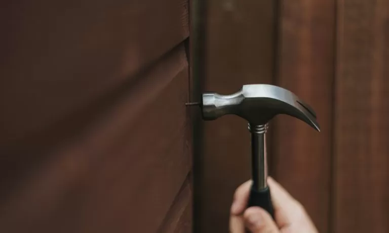 a-homeowner-using-a-nail-and-hammer-to-hang-a-picture