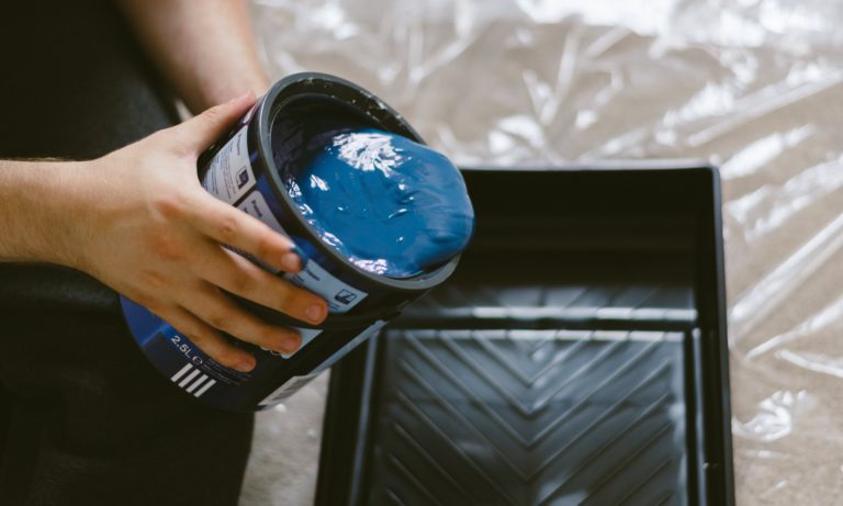 blue-paint-being-poored-into-a-container-in-preparation-of-painting-a-bookcase