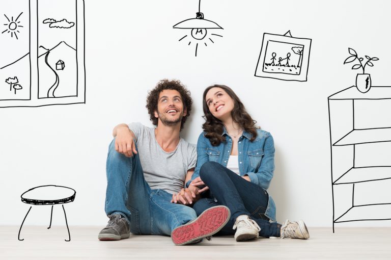 young couple wearing jeans and denim shirts sitting holding hands.