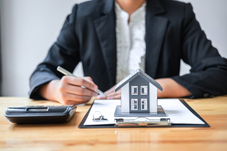 Real estate agent working sign agreement document contract for house insurance approving purchases for client with house model and key on table.