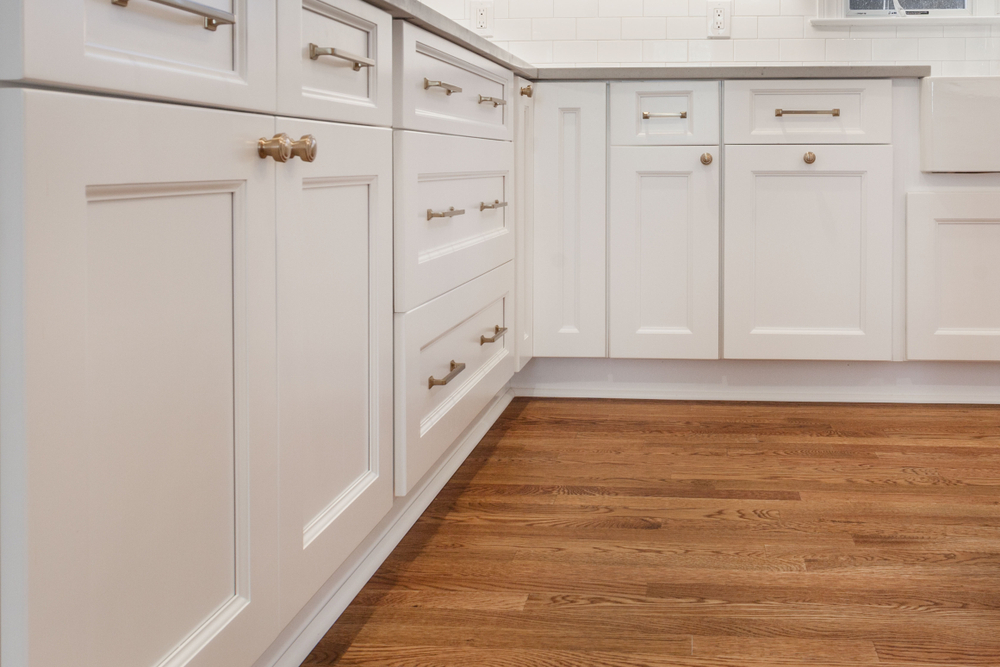 White kitchen built with shaker style cabinets. Shows cabinet details and brushed gold hardware knobs and pulls