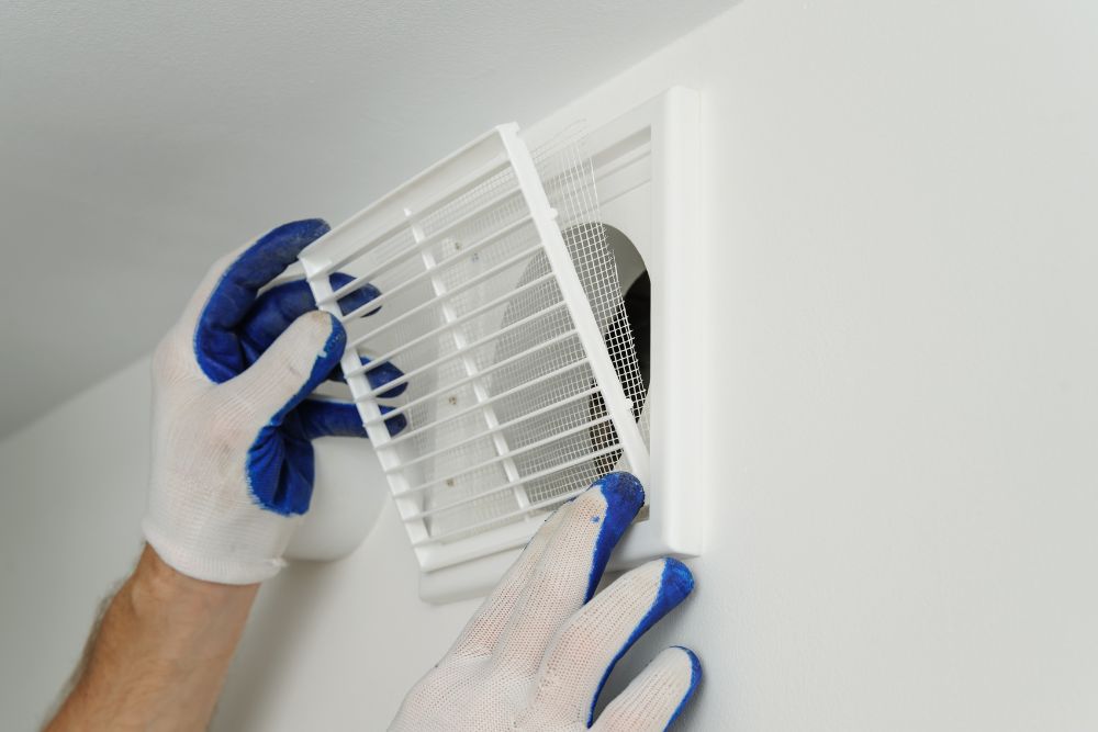 Worker installs ventilation grille.